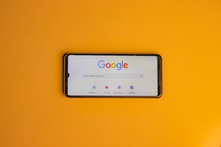 pexels-photo-16564263-16564263 Smartphone displaying Google search page on a vibrant yellow background.